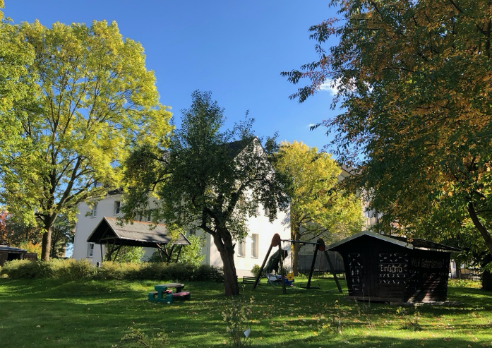 Haus in einem grünen Garten mit Bäumen und Schaukel